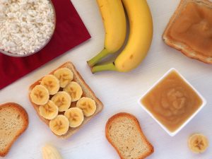 Foods included in the BRAT diet: bananas, rice, applesauce, toast. Food to consume while diarrhea or stomach virus. Flat lay.