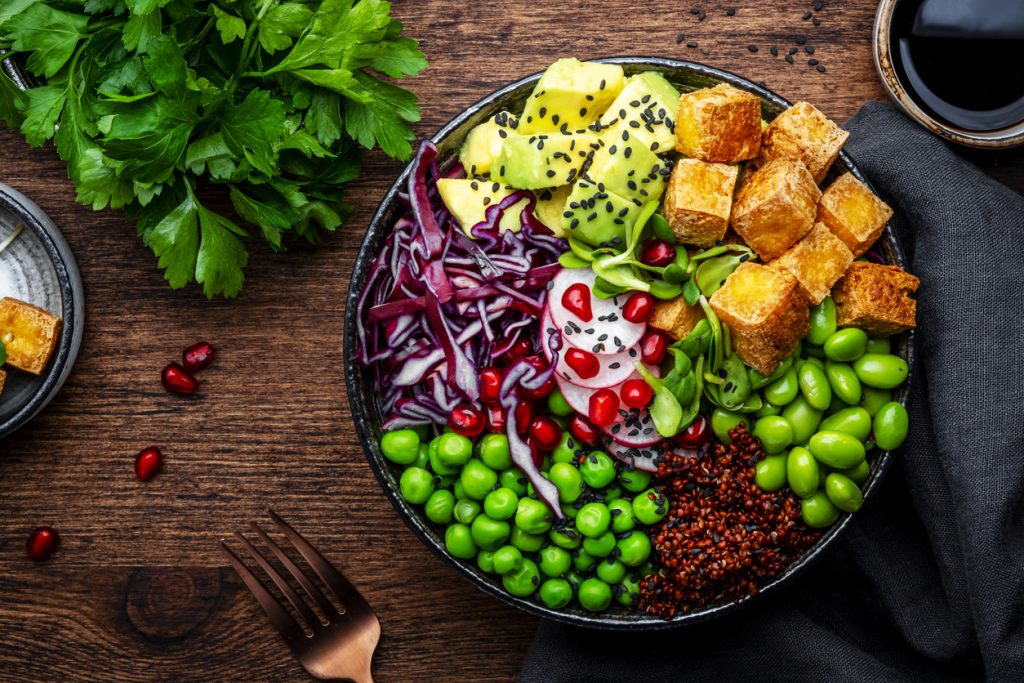 Vegan Bowl for balanced diet with tofu, quinoa, vegetables and legumes. Wooden table background, top view